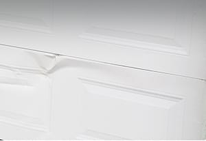 Residential garage door with dent in panel needing garage door repair service