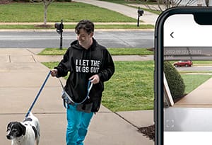 Young male dog walker using the LiftMaster myQ technology to open the homeowner's garage door