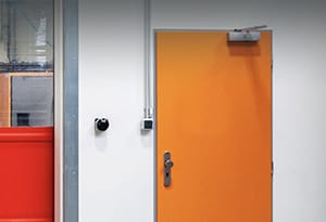 Bright orange commercial pedestrian (man) door installed in a business facility