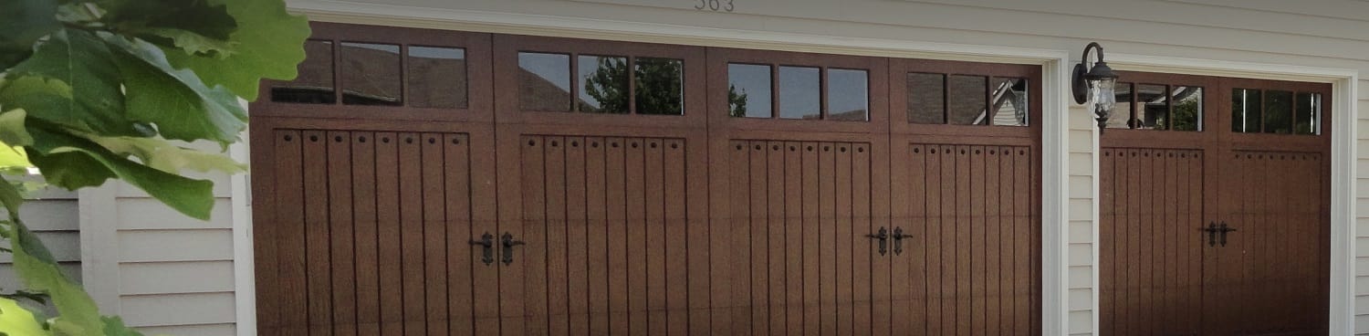 Residential custom carriage garage doors with windows and ornamental exterior hardware