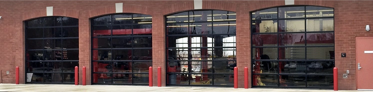 Commercial full view glass garage doors on an oil change facility who rely on a garage door maintenance program from AV Overhead