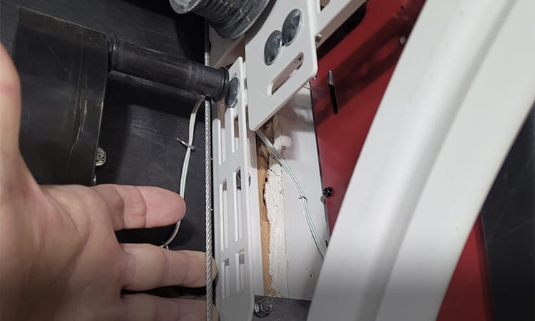 Garage door cable running up the track and winding around the drum to help move the door up and down smoothly with the spring.