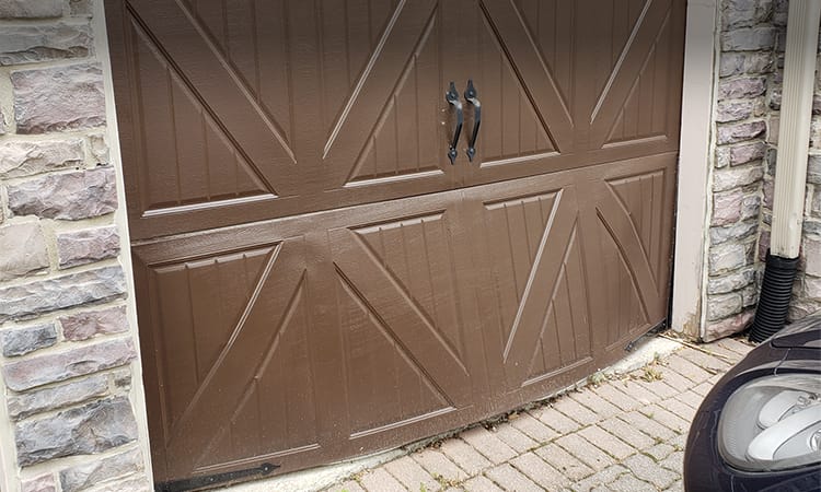 Residential garage door that has been hit by a car from inside with door dent in need of repair