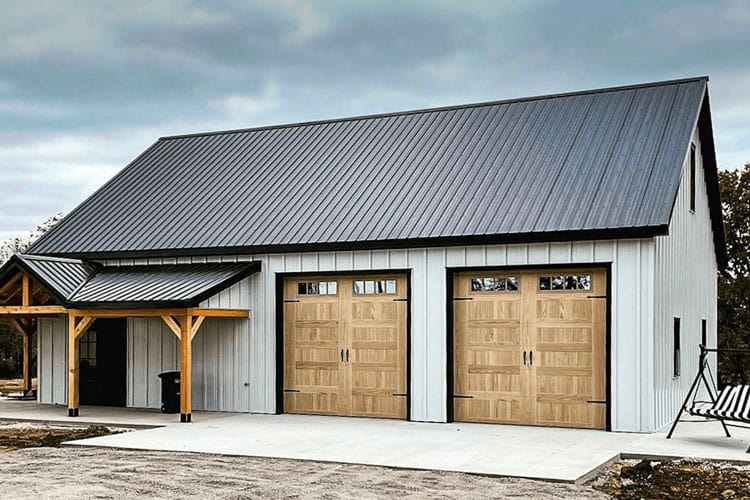 Two single stamp steel carriage garage doors with an accent light oak finish and windows