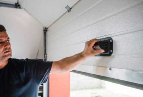 Man manually opening his garage door after his opener is not working